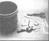 All you need to make a chicken feeder is a paint bucket, stove bolts, clothesline, and a dowel.